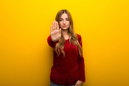 年轻女孩在充满活力的黄色背景下做停止手势,否认认为错误的情况照片