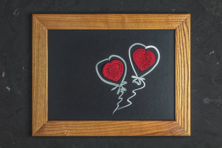 情人节贺卡用红毛钩针心在黑色表面木框，俯视，平躺，复制空间。