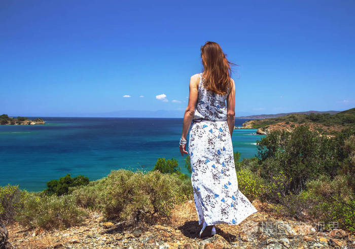 年轻女孩穿着长裙子在海滩上眺望远方浪漫放松的理念等待