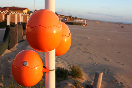 可爱的橙色鸡蛋，椭圆形的球，在海边充电手机。海滩上智能手机的充电电池。绝妙的主意