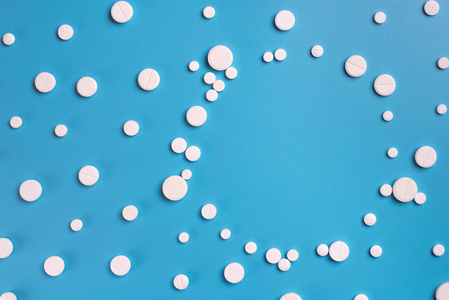 蓝红三色的药丸从一个没有盖子的白色塑料瓶中飞出,落在地上,背景凌乱