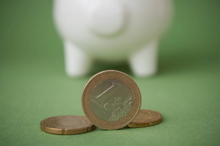 绿色背景下白色储蓄罐前的欧元硬币特写