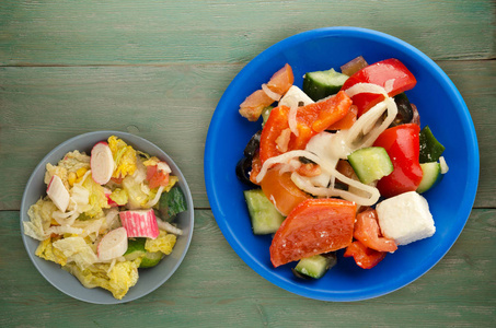 木制背景上的希腊沙拉。 希腊沙拉在盘子的顶部视图。 健康食品