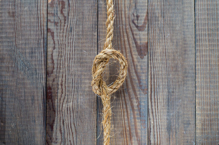 绳子在木制背景上的结。 绳子与结在空白古董棕色乡村木材背景与复制空间。