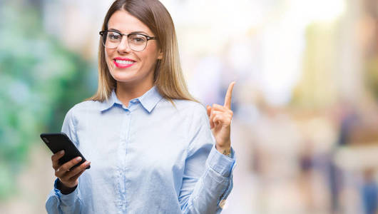 年轻漂亮的商务女性用智能手机在孤立的背景下发短信，非常高兴地用手和手指指向一边