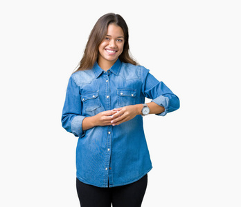 年轻漂亮的黑发女人穿着蓝色牛仔衬衫，双手分开，手指交叉微笑，轻松愉快。 成功和乐观