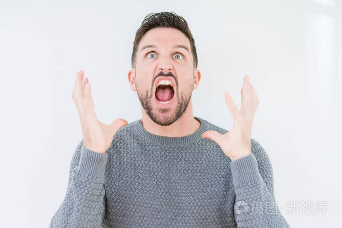 年轻英俊的男人穿着休闲毛衣,在孤立的背景上疯狂疯狂地大喊大叫,表情