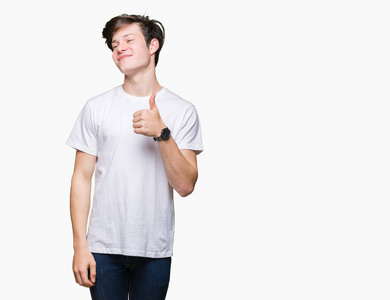 年轻英俊的男人穿着休闲的白色T恤，在孤立的背景下，用手做快乐的拇指向上的手势。 赞许的表情看着相机显示成功。