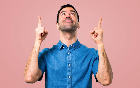 一位穿着蓝色衬衫的帅哥用食指指着粉红色背景上的一个好主意