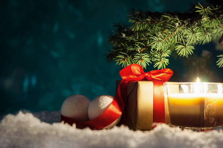带有红色丝带和雪上球的圣诞礼品盒。 圣诞节或新年背景与冷杉树枝，装饰蜡烛和礼品盒与复制空间。 贺卡模板