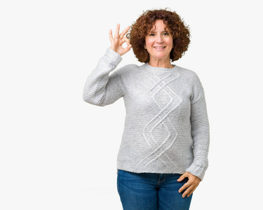 漂亮的中老年妇女穿着冬天的毛衣，在孤立的背景上微笑，积极地做着好的手势，用手和手指。 成功的表达。