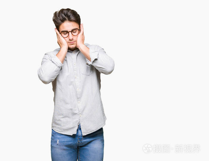年轻的英俊男子戴着眼镜，戴在孤立的背景上，手在头上疼痛，因为压力。 偏头痛。