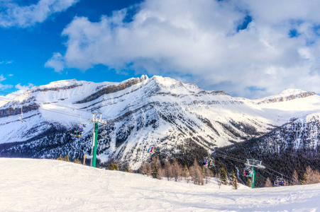 无法辨认的滑雪者和滑雪板上的椅子升降机上的滑雪坡在雪山范围内的加拿大落基山脉。