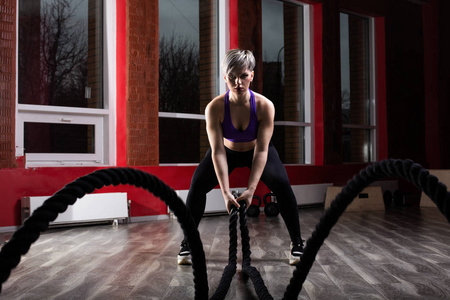 健身和肌肉发达的女人在健身工作室用战绳锻炼。 体育运动中的女运动员正在进行跳绳运动