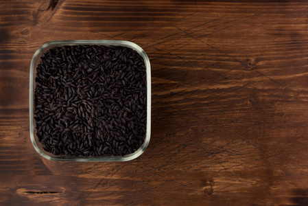 木制桌子背景上的一碗黑野米饭