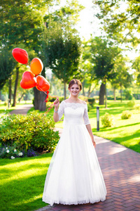 一个快乐的新娘手中拿着气球，以心脏的形式。 公园里大自然中的夏季婚礼。