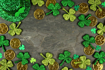 圣帕特里克日框架与三叶草，金币和妖精帽子在黑暗的石板背景