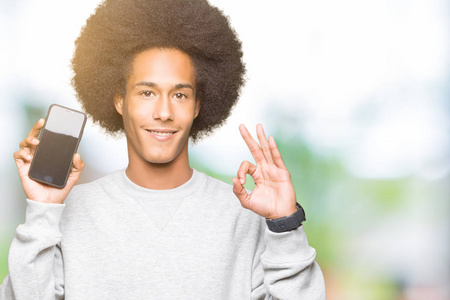 年轻的非洲裔美国男子，有非洲头发，显示智能手机屏幕，用手指做OK标志，优秀的标志