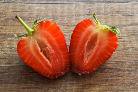 草莓在木制背景上，草莓被切成两部分。浆果