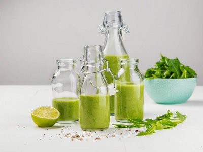 新鲜制作的健康绿色冰沙，装在白色背景的瓶子里。 水果蔬菜和种子成分。 接近复制空间。 生活方式。 垂直的。