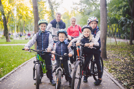 主题家庭体育度假公园在自然。 大友好的高加索家庭六人山地自行车骑在森林里。 孩子们兄弟姐妹站在父母的背景上一排。