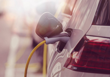 电力电缆充电电动汽车用电充电电池在车站为新的旅行充电。清洁环保车辆与新的电力发动机。关心环境骑混合动力汽车。创新运输