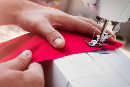 裁缝的手在缝纫机上工作，把注意力集中在针上