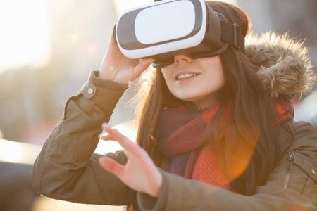 年轻女孩在玩现代虚拟现实眼镜用于移动游戏应用。使用带有创新3D耳机的移动应用程序。