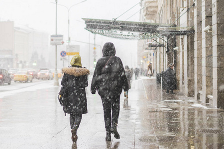 人们在雪下走在城市街道上