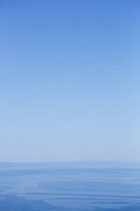 简单的蓝色背景。美丽的亚得里亚海在晴朗的蓝天下在克罗地亚。最小的壁纸，有良好的自然景观。垂直的水景观。受欢迎的夏季旅行目的地