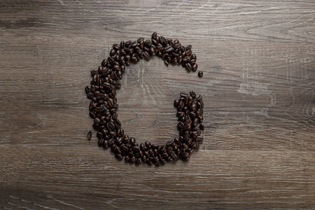 黑烤咖啡豆排列在木桌上，呈文字字母g的形状