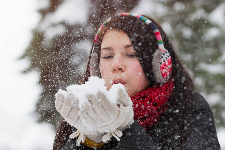 一个少女在冬天用手吹着蓬松的雪