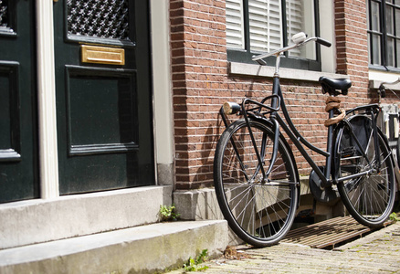 复古风格的自行车停在阿姆斯特丹市的房子附近。 荷兰的健康城市交通。 老式自行车，大轮子