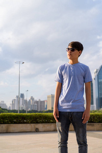 年轻的亚洲十几岁的男孩戴太阳镜, 而放松在