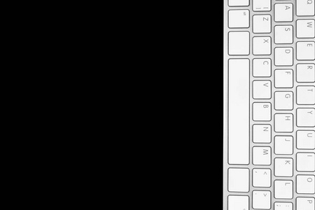 关闭商业工作场所的视图，无线计算机键盘隔离在黑色背景上。 有复印空间的办公桌。 空的空间。 顶部视图