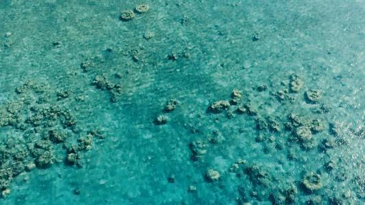 令人叹为观止的空中无人机图像，在平静的天气平坦的水和令人难以置信的五颜六色的海洋床周围，一个偏远的小热带岛屿