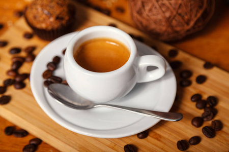 一杯带泡沫的香浓咖啡。 白色杯子里的咖啡和散落在木制背景上的咖啡豆