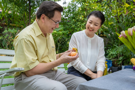 亚洲老年夫妇正在互相照顾，剥橘子吃。 家庭观念夫妻观念