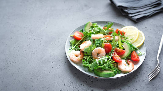 鳄梨虾沙拉与木耳和西红柿在灰色石头背景复制空间。 健康饮食绿色沙拉与虾对虾牛油果樱桃番茄和木耳。