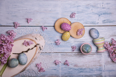 快乐复活节卡片模板与粉红色风信子花和彩色鸡蛋的木制背景