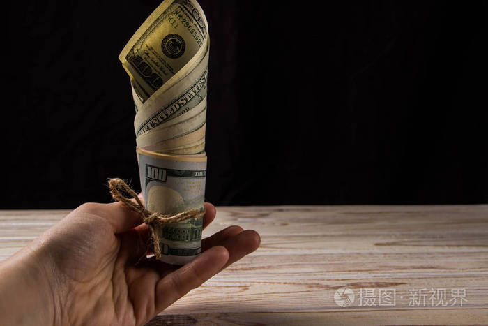 双手捧着一把钞票在黑色背景上