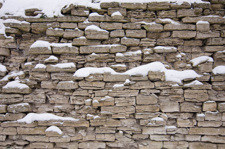 旧的石墙。 旧城堡的墙上覆盖着雪。 灰色背景