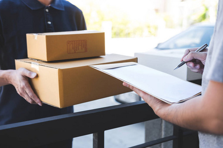 邮寄包裹送货员把包裹箱交给收件人,年轻人在家里从邮寄快递处签收