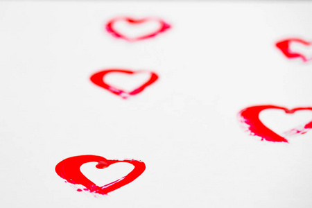 s day. Hearts are painted in red in a row, on white paper. Backg