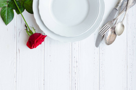 s Day romantic tabble setting with red rose, plates, cutlery on 