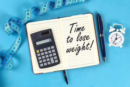 健康的生活方式概念与记事本。 减肥或饮食概念。 计算器时钟测量磁带上的蓝色桌子背景与复制空间的设计。 上面的风景。