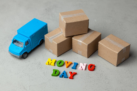 搬家的一天。通过旅行到新的公寓或办公室来运输。灰色背景上的纸盒和卡车