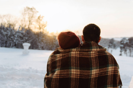 一个年轻的男人和女人坐在一起看冬天的日落。