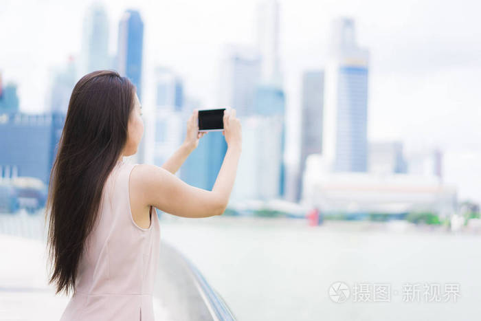 美丽的亚洲女人用智能手机或手机拍照