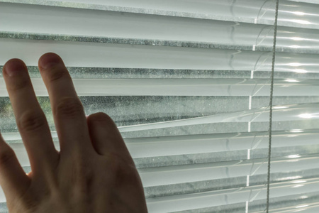 值班人员在阳光明媚的日子里,一只手打开百叶窗.照片